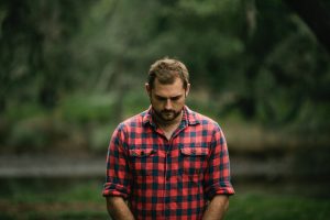 Man looking down and thinking about the type of soil his heart is made of.