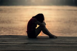 Girl curled up feeling sad. God does not punish us, but rather disciplines us.
